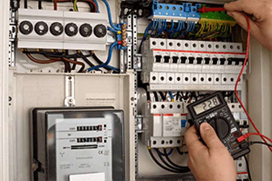 Les mains d'un électricien utilisent un multimètre pour vérifier les disjoncteurs d'un tableau électrique à côté d'un compteur.